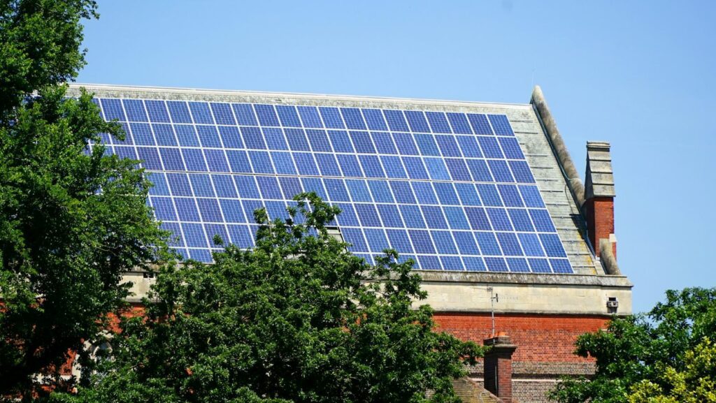 Solar panels on a large roof with trees in the foreground
