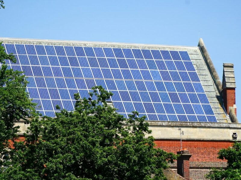 Solar panels on a large roof with trees in the foreground